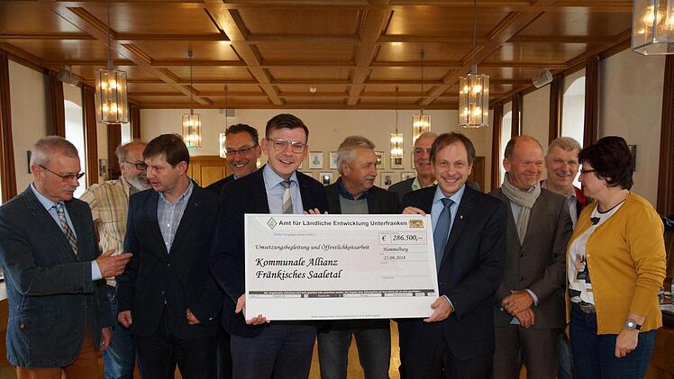 Bürgermeister Armin Warmuth (vorne, Dritter von links) nimmt im Kreise der Bürgermeisterkollegen und des Allianzmanagers Holger Becker (vorne, Zweiter von links) den Förderscheck von Otto Waldmann vom Amt für ländliche Entwicklung entgegen.  Foto: Arkadius Guzy