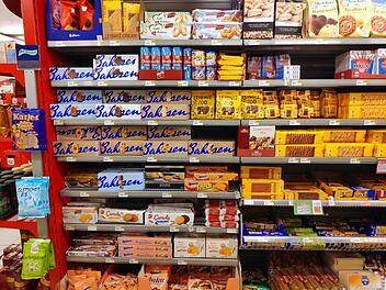 Regale voller Kekse und Snacks einer bekannten deutschen Marke. Verpackungen in Gelb und Blau dominieren. Produkte umfassen Leibniz und Bahlsen, Outlet in der Nähe von Bamberg bald eröffnet.