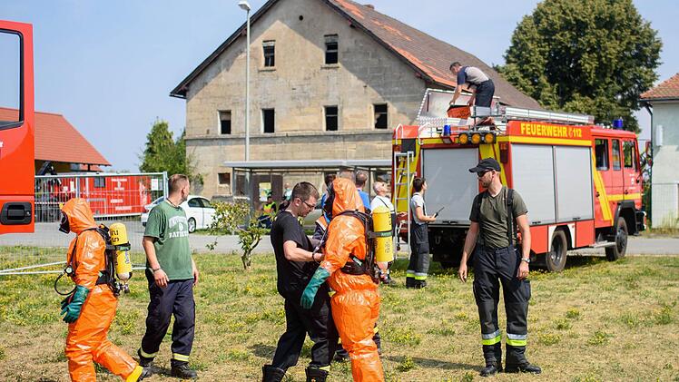 Einsatzkräfte der Feuerwehr mit Ganzkörper-Schutzanzügen sitzen am 11.08.2015 in Engelmannsreuth (Bayern) in einem Einsatzfahrzeug. Bei Engelmannsreuth ist ein F-16 Kampfjet der US-Streitkräfte abgestürzt. Foto: Nicolas Armer/dpa