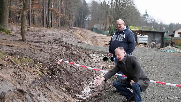 Bürgermeister Helmut Blank (vorn) und Ortssprecher Klaus Schebler an einem der neuen Gräben, die das Wasser um den Ort leiten. Die beiden befinden sich wie der Graben bereits im Landkreis Rhön-Grabfeld.  Foto: Thomas Malz