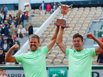 Kevin Krawietz (l) und Andreas Mies jubeln mit dem Pokal nach ihrem Turniersieg. Foto: Pavel Golovkin/AP/dpa
