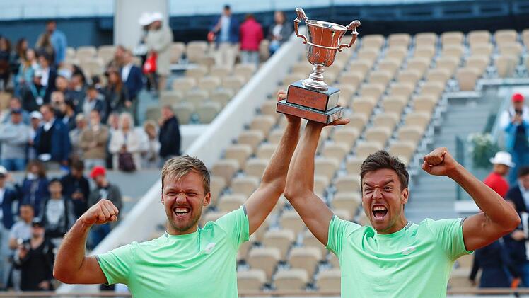 Kevin Krawietz (l) und Andreas Mies jubeln mit dem Pokal nach ihrem Turniersieg. Foto: Pavel Golovkin/AP/dpa