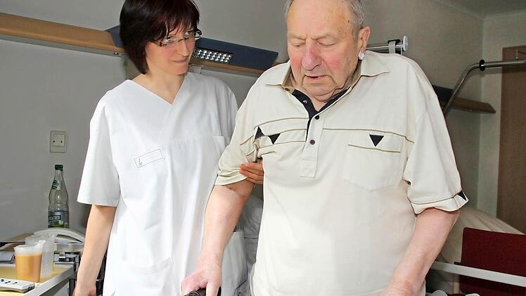 Mit ein bisschen Unterstützung von Krankenschwester Gabriele Schott schafft Alfred Dietz es wieder, die ersten Schritte mit dem Rollator zu gehen. Vom Zimmer auf den Klinikflur und zurück - nicht viel, aber ein Anfang, über den der 79-Jährige sehr froh ist. Foto: Dagmar Besand