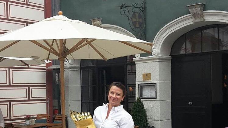 Julia Humpert, Mitarbeiterin im "Goldenen Kreuz", hält die heruntergefallene Metall-Fahne in Händen. Foto: Coburger Tageblatt
