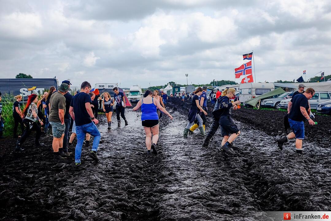 Metal-Fans laufen am 04.08.2016 in Wacken (Schleswig-Holstein) auf dem Gelände des Wacken Open Air durch den Matsch.