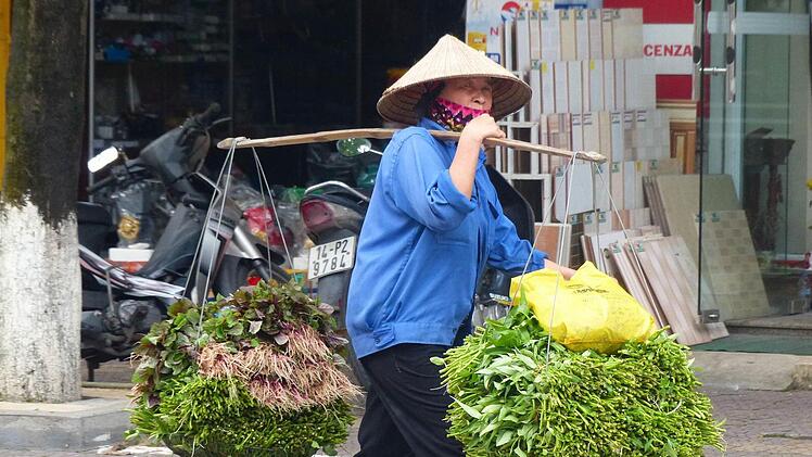 Frühmorgens läuft diese Frau durch eine vietnamesische Kleinstadt, um ihr frisches Gemüse an den Mann zu bringen.