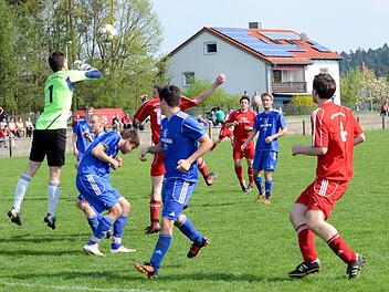 Heßdorfs Keeper Allerdissen klärt mit beiden Fäusten vor dem Gästestürmer, seine Vorderleute (blaue Trikots) ziehen vorsichtshalber die Köpfe ein. Foto: herzopress