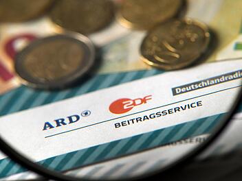 Auf einem Tisch liegt Münzgeld auf Formularen für Bürgerinnen und Bürger zu den Rundfunkbeiträgen ARD, ZDF und DRadio.Foto: Arno Burgi/dpa-Zentralbild/dpa