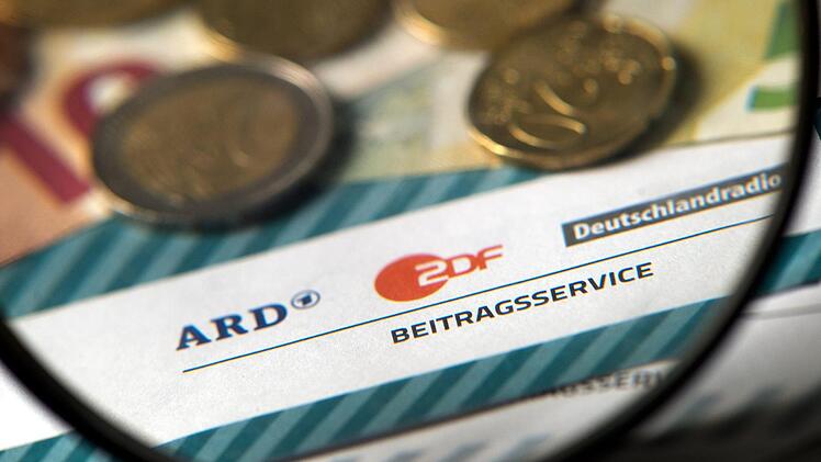 Auf einem Tisch liegt Münzgeld auf Formularen für Bürgerinnen und Bürger zu den Rundfunkbeiträgen ARD, ZDF und DRadio.Foto: Arno Burgi/dpa-Zentralbild/dpa