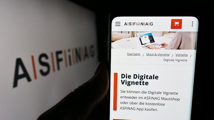 Person mit Mobiltelefon, auf dessen Display die Webseite des österreichischen Autobahninfrastrukturunternehmens ASFINAG vor dem Logo zu sehen ist. Fokus auf die Mitte des Displaybildschirms. Stuttgart, Germany - 06-11-2024: Person holding cellphone with webpage of Austrian motorway infrastructure company ASFINAG in front of logo. Focus on center of phone display.