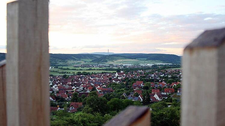 Blick vom Dach der Dreifaltigkeitskapelle aus über die Stelen und das Flurkreuz am Heinig auf die Ortschaft Fuchsstadt und das idyllische Saaletal.