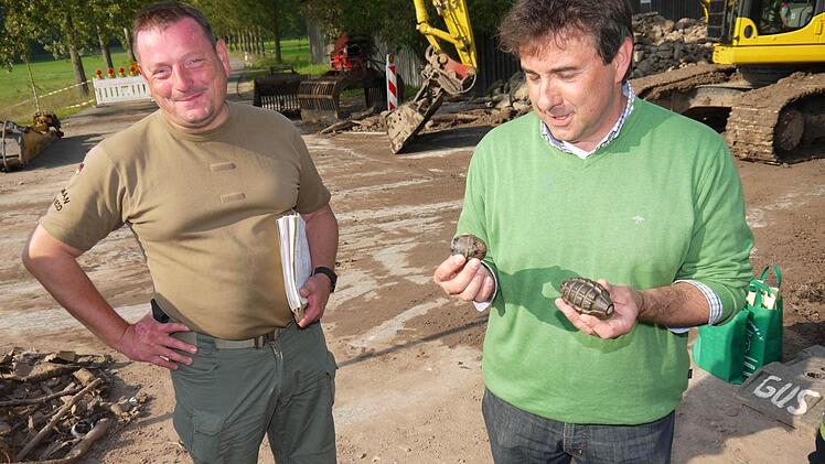 In der rechten Hand hält Bürgermeister Rolf Rosenbauer eine deutsche Handgranate, in der linke eine amerikanische. Heinrich Bernhard Scho ist froh, dass er in Untersiemau endlich Fertig ist.