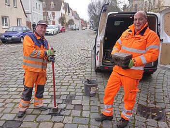 Willi (links) und Michael vom Höchstadter Bauhof füllen die Löcher der herausgearbeiteten Steine mit Kaltasphalt.   Foto: Andreas Dorsch