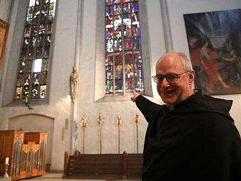 Augustinerpater Markus Reis zeigt auf die bunt bemalten Fenster aus dem 15. Jahrhundert. Diese werden in einem ersten Bauabschnitt grundlegend saniert. Foto: Markus Hauck/pow