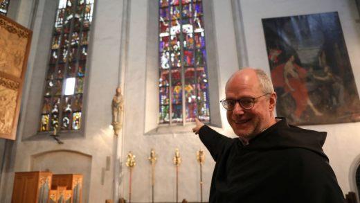 Augustinerpater Markus Reis zeigt auf die bunt bemalten Fenster aus dem 15. Jahrhundert. Diese werden in einem ersten Bauabschnitt grundlegend saniert. Foto: Markus Hauck/pow
