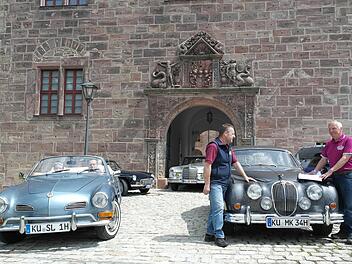 Jaguar-Limousine, Karman-Ghia, MGB- und Mercedes-Coupé vor dem Tor zum Schönen Hof: Die Mitglieder des Oldtimer-Stammtisches Kulmbach haben auf der Plassenburg schon mal probeweise geparkt. Rechts OSK-Chef Walter Schaller, der mit Heiko Schlensog die letzten Details bespricht, links im Cabriolet Alexandra und Stephan Lauterbach. Foto: Peter Müller