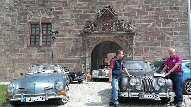 Jaguar-Limousine, Karman-Ghia, MGB- und Mercedes-Coupé vor dem Tor zum Schönen Hof: Die Mitglieder des Oldtimer-Stammtisches Kulmbach haben auf der Plassenburg schon mal probeweise geparkt. Rechts OSK-Chef Walter Schaller, der mit Heiko Schlensog die letzten Details bespricht, links im Cabriolet Alexandra und Stephan Lauterbach. Foto: Peter Müller