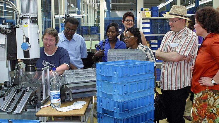 Wie Behinderte ihren Fähigkeiten entsprechend erfolgreich in Arbeitsprozesse integriert werden können, erfuhren die Gäste aus Tansania beim Rundgang durch die WEFA. Annett von Löffelholz (links) produziert hier Sitzversteller für Brose. Begleitet wurden die Afrikaner von ihren Gastgebern in der ersten Woche, Dekanatsmissionspfarrer Andreas Neeb und WEFA-Elternbeiratsmitglied Eleonore