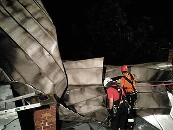 Das Blechdach verfing sich an einem Kamin. Die Feuerwehrleute mussten die Teile auseinanderflexen und abseilen. Foto: Feuerwehr Coburg