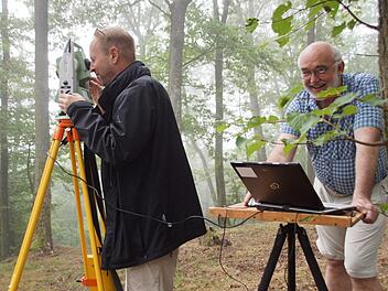 Morgens halb neun im nebligen Wald: die Stimmung ist gut bei Claus Schaffranek am Laptop und Michael Mark am Tachymeter. Beide sind ehrenamtliche Helfer bei der geoelektrischen Prospektion am Eltmanner Burgstall. Foto: Christiane Reuther