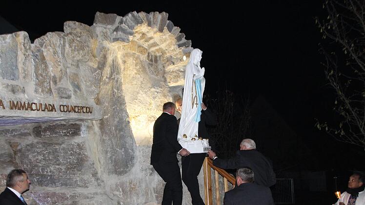 Die Erbauer der Grotte heben die Marienfigur an ihren Platz. Fotos: Evi Seeger/Andreas Dorsch