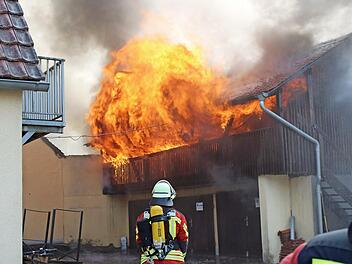 Flammen schlagen aus einem Nebengebäude in Holzbauweise.