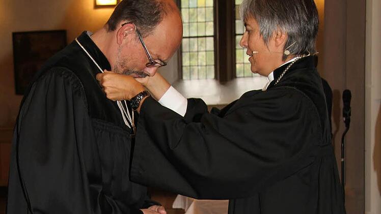 Regionalbischöfin Dorothea Greiner legte dem neuen Dekan Thomas Kretschmar, der zuletzt in Kaufbeuren tätig war, die Hand auf und hängte ihm das Kreuz um: Damit installierte sie ihn offiziell in seinem neuen Amt.  Foto: Sonny Adam