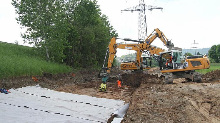 Mit Planen und Steinen wird der Straßendamm der Bundesstraße befestigt.