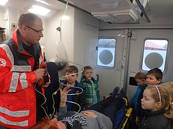 Rettungssanitäter Armin Stelzner erläuterte den Kindern die Geräte, die zur Erstversorgung von Verletzten und Kranken im Rettungswagen vorhanden sind. Als Patientin hat auf der Rettungsliege Kinderpflegerin Brigitte Winkler Platz genommen. Foto: Helmut Raab