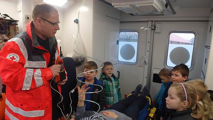 Rettungssanitäter Armin Stelzner erläuterte den Kindern die Geräte, die zur Erstversorgung von Verletzten und Kranken im Rettungswagen vorhanden sind. Als Patientin hat auf der Rettungsliege Kinderpflegerin Brigitte Winkler Platz genommen. Foto: Helmut Raab