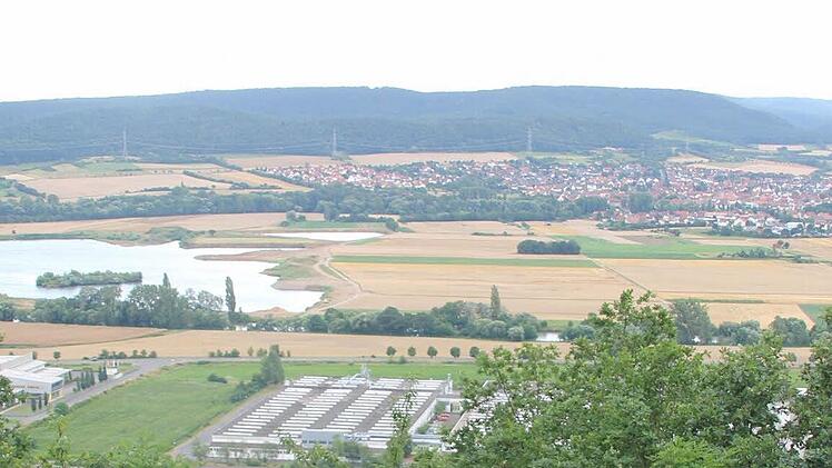 Das Maintal mit Blick auf Sand: Links liegt das aktuelle Sand- und Kiesabbaugebiet. Rechts neben der Wasserfläche befindet sich das Gelände für die beantragte Ausbeute. Im Vordergrund sind gewerbliche Gebäude von Zeil zu sehen und wie ein grünes Band zieht sich der Main von links nach rechts durch das Bild.  Foto: Klaus Schmitt