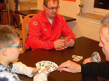 Fritz Trautner (r.) bringt Bastian das Schafkopfen bei. Bastian Vater Andreas Schnell (M.) begrüßt das Interesse seines Sohns.  Foto: Lengenfelder