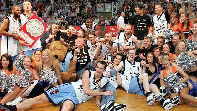 Derrick Taylor (l.) h&auml;lt die Meistertroph&auml;e in H&auml;nden, Steffen Hamann (daneben) qualmt eine dicke Zigarre und verwandelt das "Forum" in ein Tollhaus. Am Wochenende feiern die Helden von 2005 das Zehnj&auml;hrige in der Frankenh&ouml;lle. Foto: sportpress