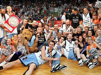 Derrick Taylor (l.) hält die Meistertrophäe in Händen, Steffen Hamann (daneben) qualmt eine dicke Zigarre und verwandelt das "Forum" in ein Tollhaus. Am Wochenende feiern die Helden von 2005 das Zehnjährige in der Frankenhölle. Foto: sportpress
