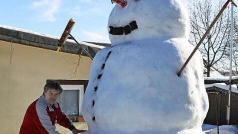 Marco Hader bessert die bereits heruntergefallenen Knöpfe seines Schneemannes wieder aus.  Foto: Michael Wunder