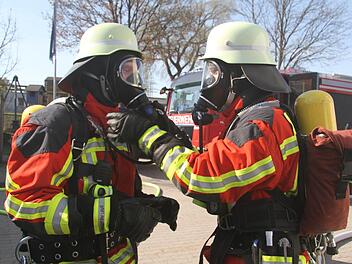 Beim Anlegen der Atemschutzausrüstung helfen sich die Feuerwehrlehrer gegenseitig Foto: Sonny Adam