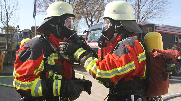 Beim Anlegen der Atemschutzausrüstung helfen sich die Feuerwehrlehrer gegenseitig Foto: Sonny Adam