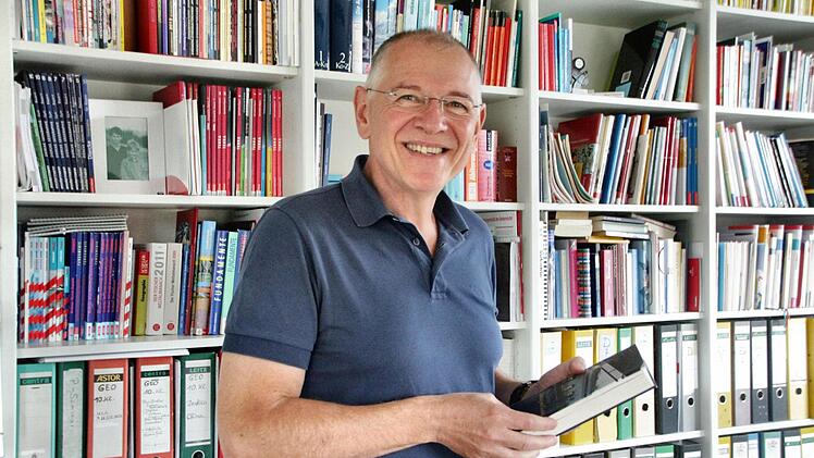 Karl Waldmann mit Lieblingsbuch (Nachtzug nach Lissabon) an seinem Lieblingsort: in der eigenen Bibliothek daheim in Heroldsbach im Öko-Haus direkt am Waldrand. Fotos: Nikolas Pelke