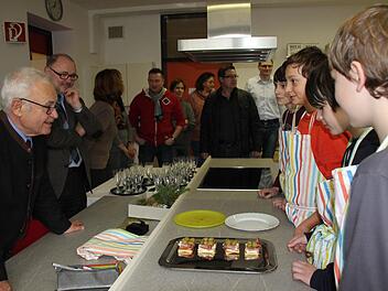 Fabian, Johanns und Florian aus der 7a (im Bild von rechts) erklären dem Landrat, was sie für ihn und die Gäste, wie Bürgermeister Herrmann oder Elternbeiräte zubereitet haben. Foto: Ralf Kestel
