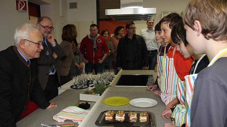 Fabian, Johanns und Florian aus der 7a (im Bild von rechts) erklären dem Landrat, was sie für ihn und die Gäste, wie Bürgermeister Herrmann oder Elternbeiräte zubereitet haben. Foto: Ralf Kestel