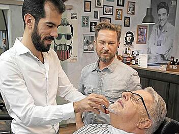 Anton Steinl aus Burghaig lässt sich von Hosein Dyab den Bart zurechtstutzen. Der 32-Jährige Syrer arbeitet seit August im Melkendorfer Barbershop von Frank Walther (Mitte). Er ist einer der ersten Schützlinge, die Steinl ehrenamtlich begleitet hat. Fotos: Peter Müller