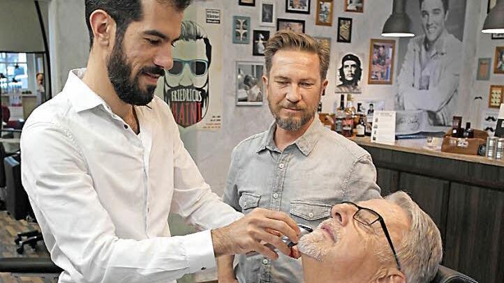 Anton Steinl aus Burghaig lässt sich von Hosein Dyab den Bart zurechtstutzen. Der 32-Jährige Syrer arbeitet seit August im Melkendorfer Barbershop von Frank Walther (Mitte). Er ist einer der ersten Schützlinge, die Steinl ehrenamtlich begleitet hat. Fotos: Peter Müller