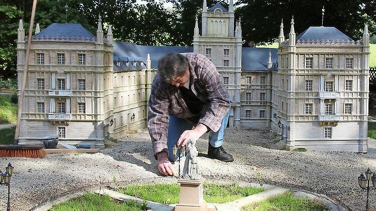 Michael Schelhammer befestigt eine Laterne am Mini-Schlossplatz, um ihm noch den letzten Feinschliff vor der Eröffnung zu geben. Ab November gehen die Gebäude dann in Winterschlaf, das heißt, sie werden überdacht und damit wetterfest gemacht.
