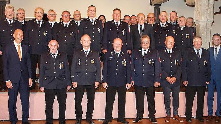 Landrat Christian Mei&szlig;ner (v. li.) sowie Kreisbrandrat Timm Vogler und B&uuml;rgermeister Andreas H&uuml;gerich (vorne v. re.) begl&uuml;ckw&uuml;nschten 22 Feuerwehrm&auml;nner zur Auszeichnung mit dem Feuerwehr-Ehrenzeichen in Gold f&uuml;r 40-j&auml;hrige Dienstzeit.