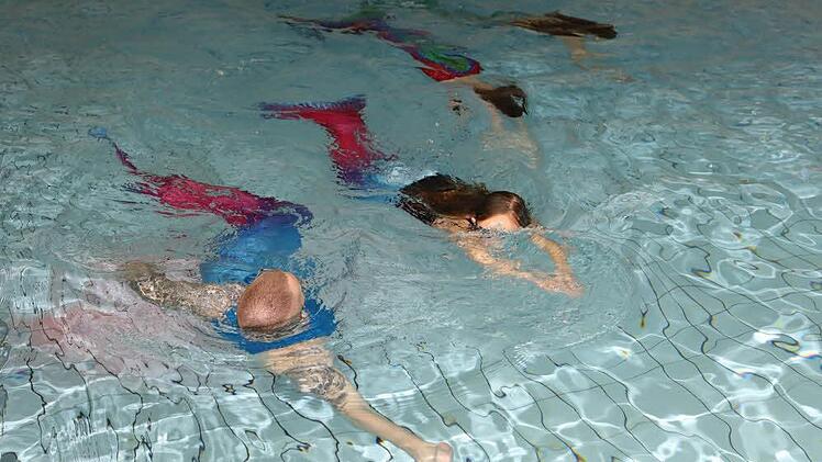 Unter Anleitung von Wassermann Oliver (vorne) lernen Lena, Lara und Maja, wie Meerjungfrauen schwimmen. Foto: Barbara Herbst