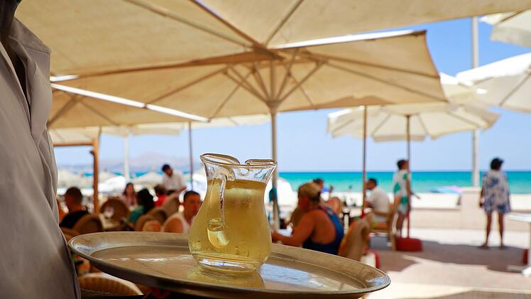 Kellner serviert am Strand einen Wein