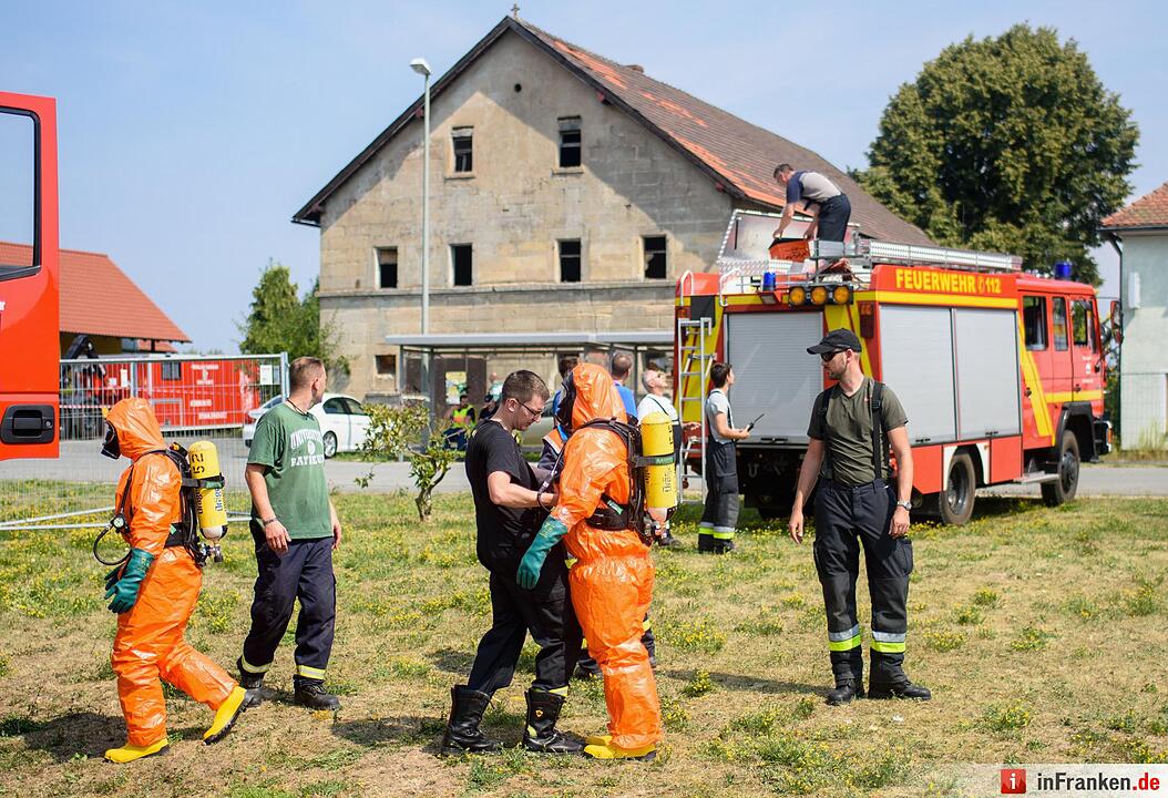 Einsatzkräfte der Feuerwehr ziehen sich am 11.08.2015 in Engelmannsreuth (Bayern) Ganzkörper-Schutzanzüge an. Bei Engelmannsreuth ist ein F-16 Kampfjet der US-Streitkräfte abgestürzt. Foto: Nicolas Armer/dpa