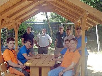 Ein gemütlicher Ort mit Schutz vor Sonne und Regen ist die neue Sitzgruppe, über die sich (stehend von links) Hotelier Christoph Wagner, Revierleiter Peter Hagemann, Reinhardt Neft und Bürgermeister Gerhard Wunder mit einigen beteiligten Azubis freuen. Foto: Susanne Deuerling