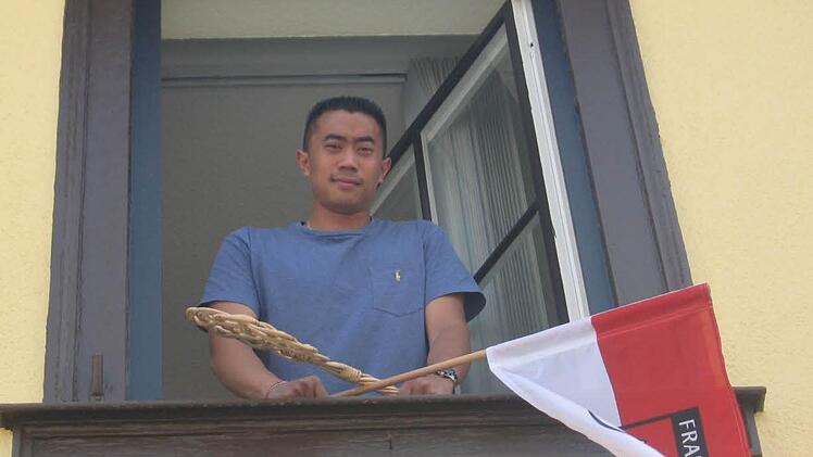Für den Fränkischen Tag lehnte sich Anthony Ith gerne etwas aus dem Fenster. Mit Frankenfahne und Teppichklopfer. Von "seinem" Büro aus hat er Blick auf den Marktplatz und das Rathaus. Foto: Markus Häggberg