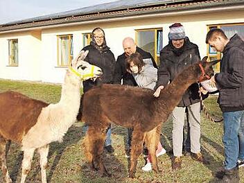 Unter Anleitung des Tierbesitzers (links) und des Fördergruppenleiters Tilo Stadelmann (Zweiter von link) durften einige Klienten der Fördergruppe ein Lama und ein Alpaka streicheln und füttern.  Foto: Alfred Thieret